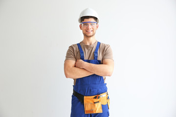 Smiling young electrician in hardhat and with glasses on white background