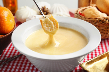 Piece of bread dipped into cheese fondue, closeup