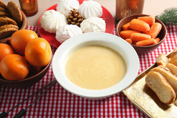 Bowl with delicious cheese fondue on table