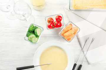 Delicious cheese fondue and vegetables on table