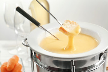 Piece of bread dipped into cheese fondue, closeup