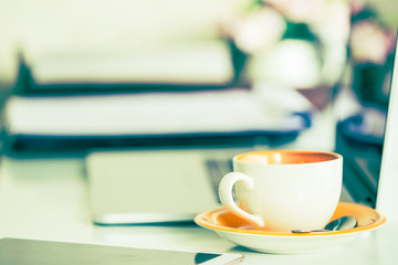 Cup of coffee and smart devices on the table close up. (Processed in vintage colour tone)