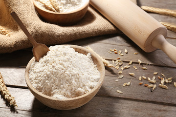 Bowl with flour on wooden table