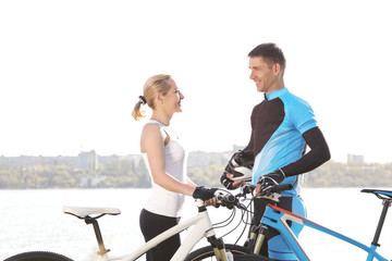 Obraz premium Sporty cyclists with bicycles near river