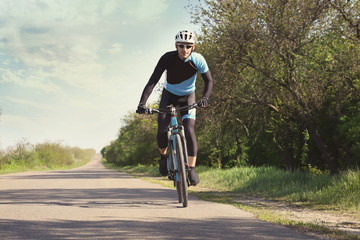 Sporty cyclist riding bicycle outdoors on sunny day