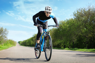 Sporty cyclist riding bicycle outdoors on sunny day