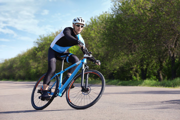 Sporty cyclist riding bicycle outdoors on sunny day