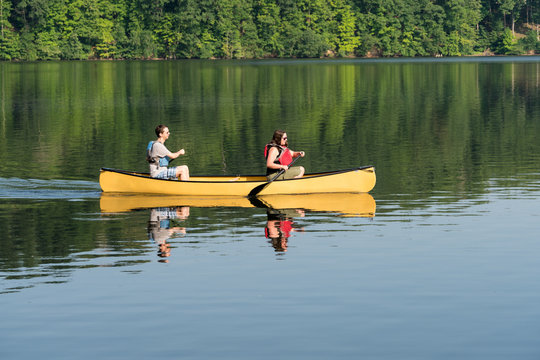 Couple paddling in yellow canoe on tree lined lake