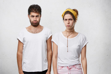 Young angry couple having sulky expressions blowing their cheeks with despair having bad...