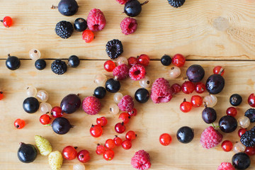 Naklejka na ściany i meble Red, white, black currant, red and black raspberries, white strawberries on wooden table as ingredient to healthy eating and drinking