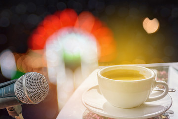 Abstract soft blurred and soft focus a cup of coffee, microphone of the stage concert light and sound with the bokeh, beam light, shadow, and lens flare effect tone background.