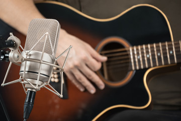 Microphone recording an acoustic guitar played by hand