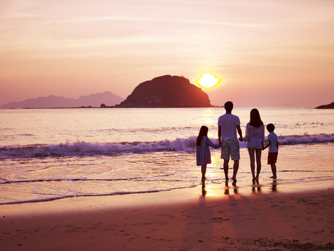 Asian Family Watching Sunrise On Beach