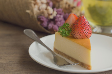 Homemade New York cheesecake on white plate decorated by strawberry and parsley. Moist and smooth classic style baked cheesecake. Copy space background of delicious strawberry New York cheesecake.