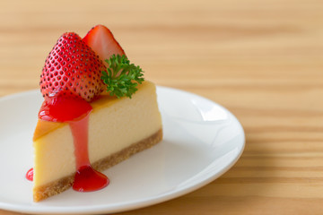 Homemade New York cheesecake on white plate decorated by strawberry,parsley and strawberry sauce. Moist and smooth classic baked cheesecake. Copy space background of delicious New York cheesecake.