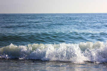 Blue seashore with waves and foam.