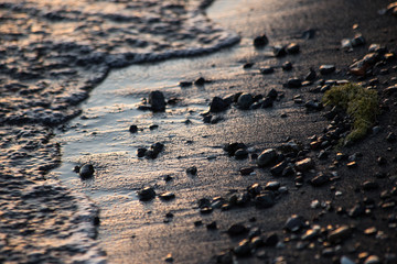 A close shot of water on a lake shore, with details of sands and little stones