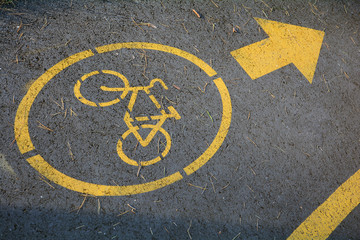The bike path. Yellow bicycle sign on asphalt background.