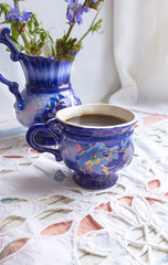 Blue cup of coffee tea chicory drink with chicory flower,  hot beverage on embroidered fabric background