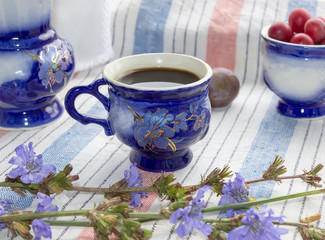 Obraz na płótnie Canvas Blue cup of coffee tea chicory drink with chicory flower, hot beverage on embroidered fabric background