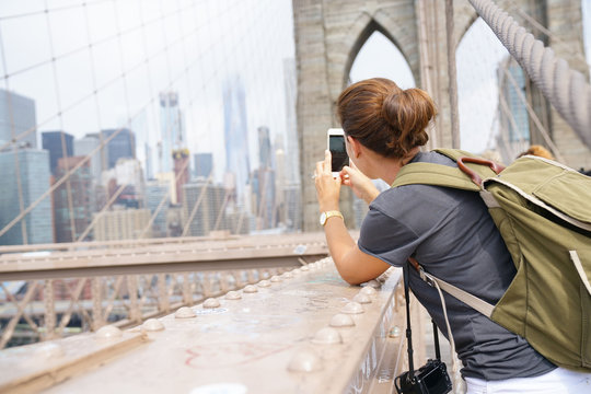Tourist on Brooklyn bridge taking picture of scenery
