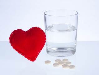 Red heart, glass of water and pills