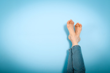 Female legs foot on foot on blue background, resting, holiday