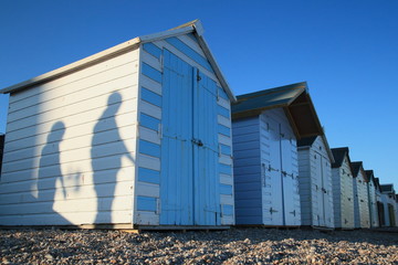 Shadows of people passing by beach huts in Seaton, Devon