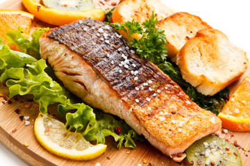 Grilled salmon with bread on wooden board on white background 