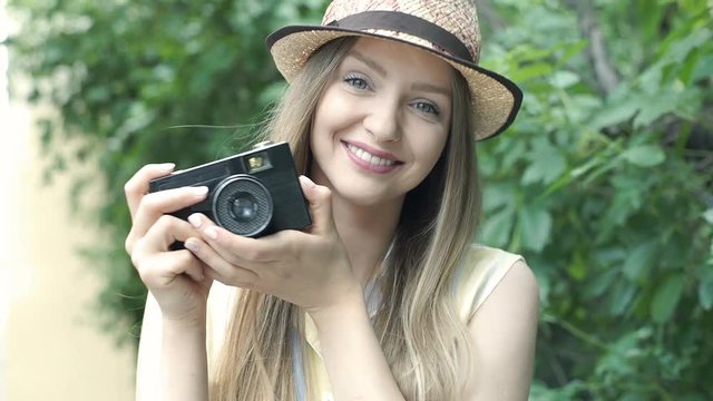Pretty girl doing photos on old camera and smiling, steadycam shot
