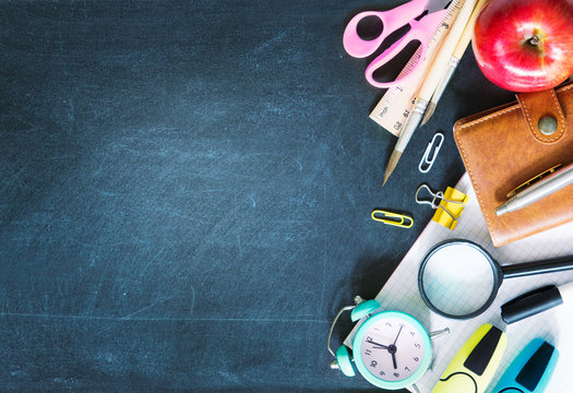 School Supplies On Black Board Background Empty Copy Space.