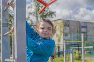 Девочка выполняет упражнения на спортивных снарядах