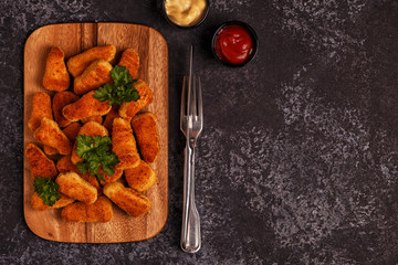 Chicken nuggets with sauces on dark background.