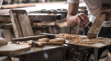 male carpenter working with a wood product, hand tools