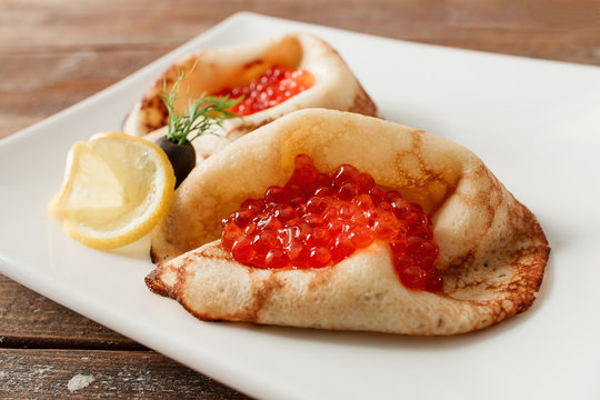 Luxury pancakes with red caviar with lemon. Russian traditional salty crepes with seafood. Shrove tuesday holiday food