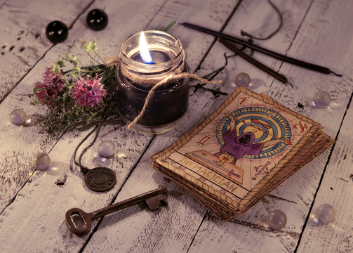 Black candle and old tarot cards on wooden planks