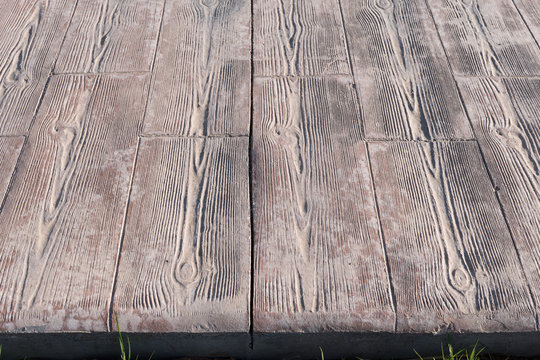 stamped concrete pavement close up detail expansion joint at middle, Wooden slats pattern, flooring exterior, decorative texture of cement paving with streaks of wood