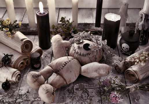 Voodoo doll with black candles and ancient scrolls
