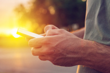 Man using mobile phone on street in sunset