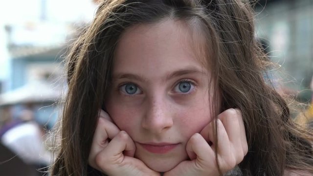 The little girl with blue eyes and freckles looks into camera and smiles