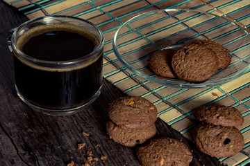 Coffee cup and cookie on wooden background.