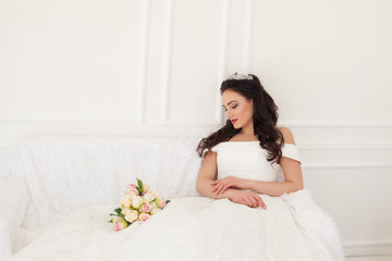 bride in wedding dress sitting on a sofa wedding bouquet