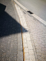 Verkehrsberuhigte Zone mit abgesenktem Bordstein und Verbundpflaster mit Schatten im Sonnenschein...