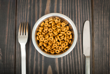 Cat food and cutlery on a wooden table.
