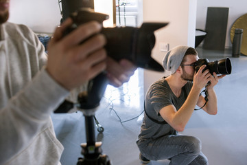 Photographer shooting at studio photo session. Creative man take professional camera and photographing somebody.Fashion photosession backstage