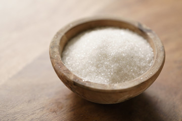 white sugar in wood bowl on wooden table