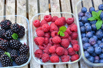 Raspberries, blue berries and black berries on a wooden garden table