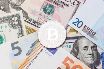 Golden Bitcoins close-up. Euro and dollars currency as a background.