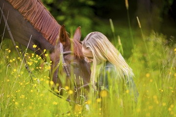 Smiling woman sitting in the meadow with her arabian horse