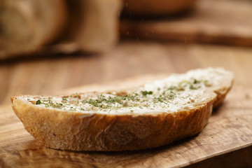 rustic wheat bread with butter and herbs on wood board